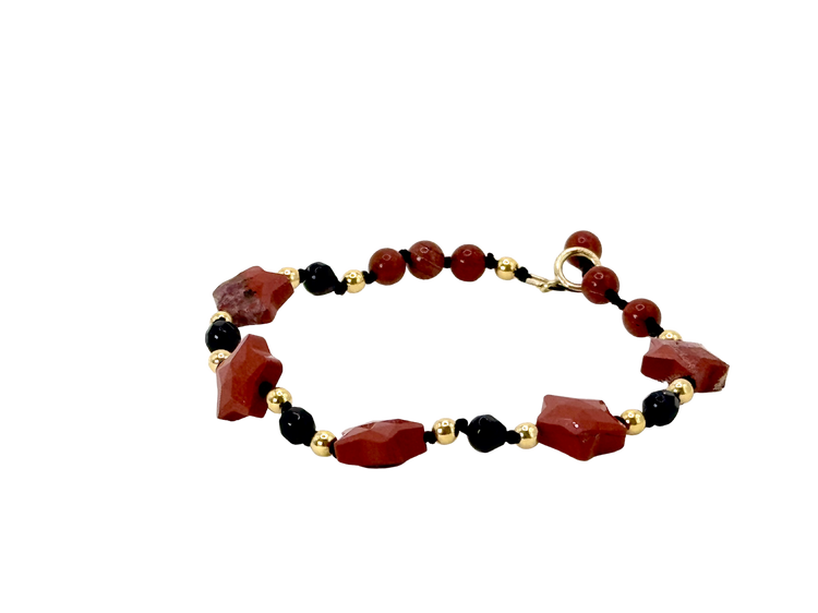 La simplicité fun du lien, la lumière des étoiles.

Bracelet sur cordon - Perles étoile en jaspe rouge - Perles d'onyx noire, jaspe rouge et en or laminé 14 carats.

J'ai noué chaque perle entre elles, comme un acte de solidarité et de compassion.