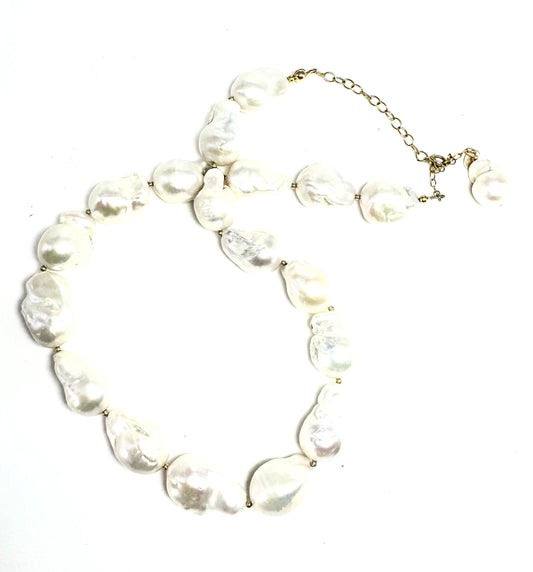 Collier sur chaîne en or laminé - Perles  keshi (perles de culture dites "baroques") 1,5cm environ, perles en or laminé 14 carats.&nbsp;

Ce collier met à l’honneur la perle keshi dans toute son authenticité. Chaque perle, naturellement formée, révèle des reflets nacrés et une texture organique qui en font une pièce unique. Assemblées à la main, elles composent un bijou à la fois moderne, raffiné et intemporel